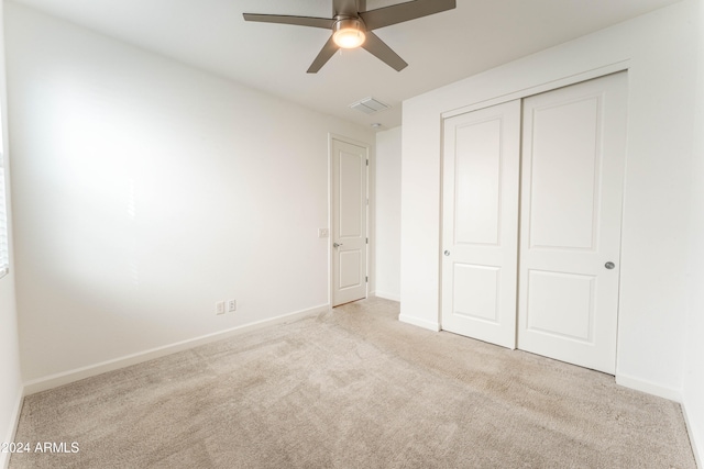 unfurnished bedroom with light colored carpet, a closet, and ceiling fan