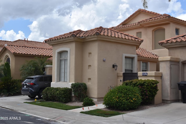 mediterranean / spanish home featuring a tiled roof and stucco siding