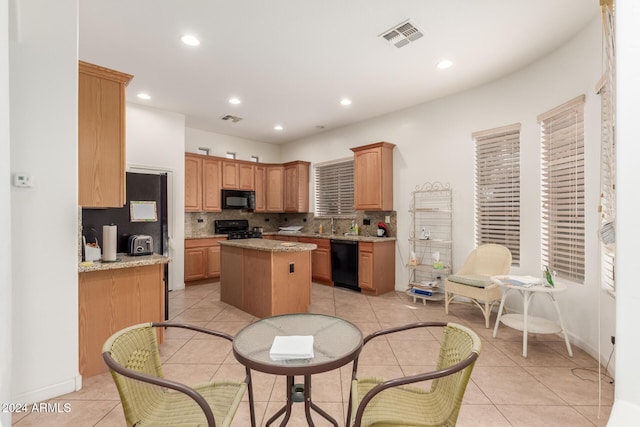 kitchen featuring light tile patterned flooring, a center island, backsplash, and black appliances