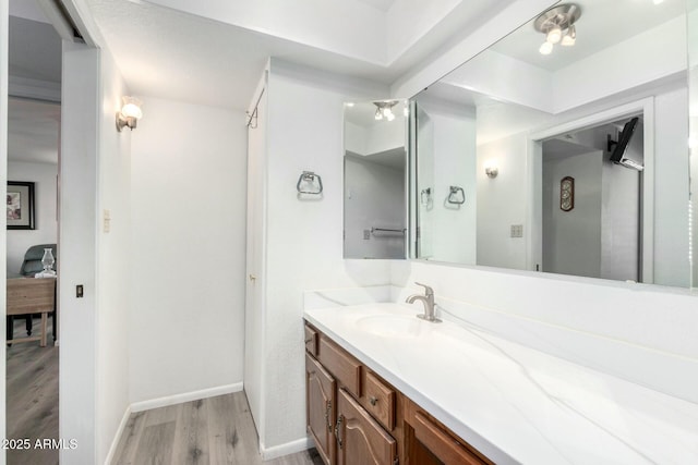 bathroom featuring baseboards, wood finished floors, and vanity