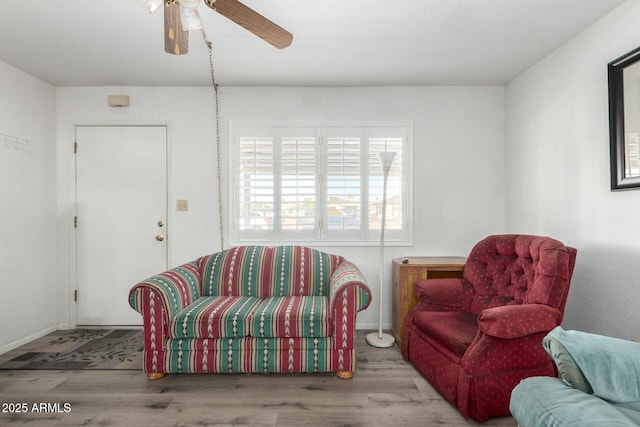 living room with wood finished floors, a ceiling fan, and baseboards