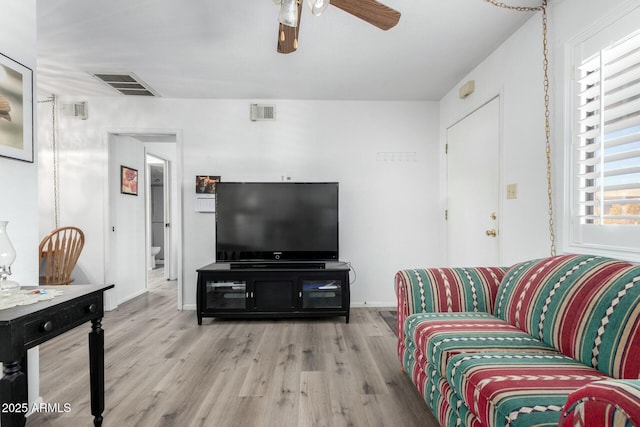 living area with wood finished floors, visible vents, and a ceiling fan