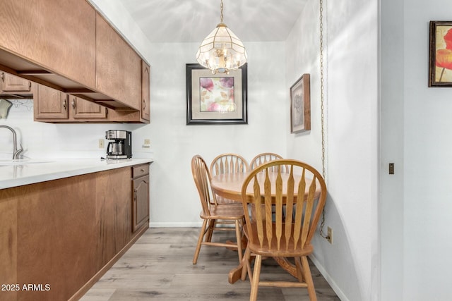 dining space with light wood-type flooring, a notable chandelier, and baseboards