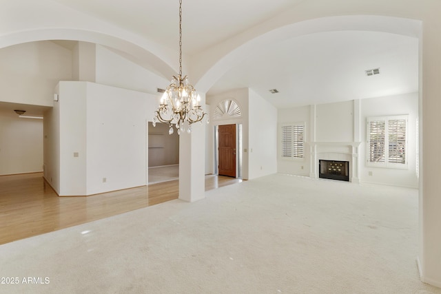 10609 E Cedar Waxwing Dr, Sun Lakes, AZ 85248 - unfurnished living room with visible vents, arched walkways, a notable chandelier, carpet floors, and a fireplace with flush hearth
