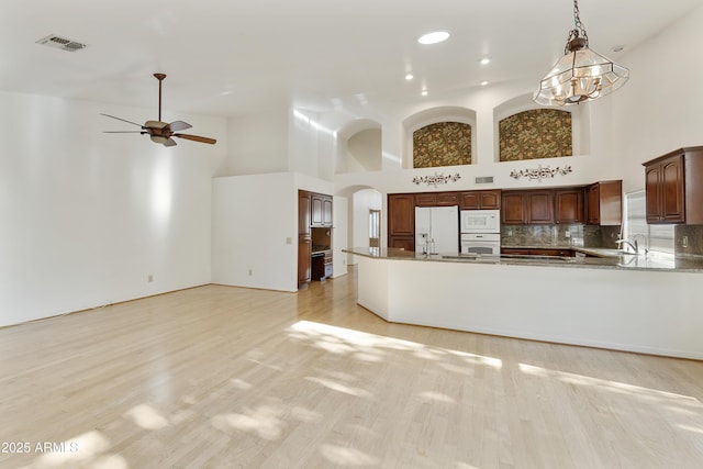 10609 E Cedar Waxwing Dr, Sun Lakes, AZ 85248 - unfurnished living room featuring arched walkways, visible vents, a high ceiling, and light wood-style flooring