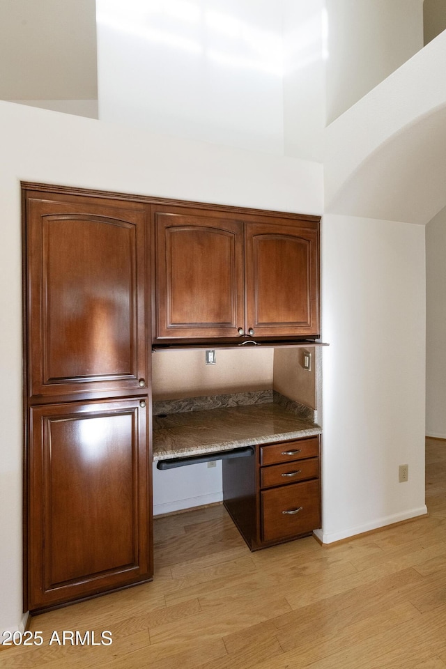 10609 E Cedar Waxwing Dr, Sun Lakes, AZ 85248 - kitchen with brown cabinetry, baseboards, light wood finished floors, and built in study area