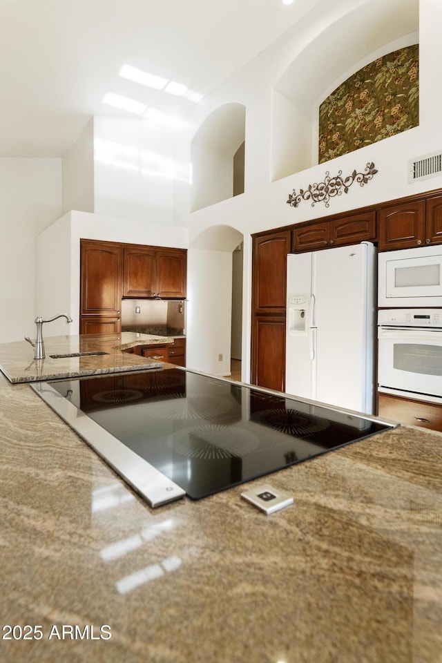 10609 E Cedar Waxwing Dr, Sun Lakes, AZ 85248 - kitchen with a towering ceiling, white appliances, light stone countertops, visible vents, and a sink
