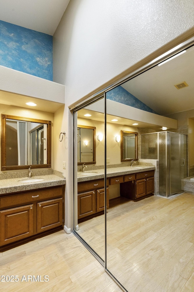 10609 E Cedar Waxwing Dr, Sun Lakes, AZ 85248 - full bathroom featuring a stall shower, wood finished floors, two vanities, and a sink