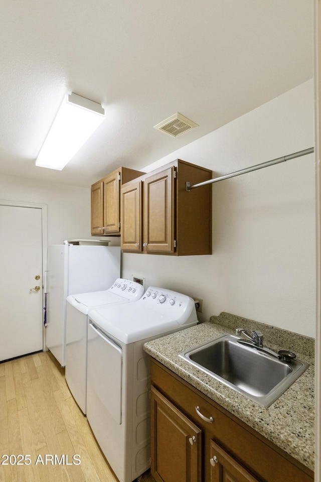 10609 E Cedar Waxwing Dr, Sun Lakes, AZ 85248 - clothes washing area with visible vents, cabinet space, washer and dryer, light wood finished floors, and a sink
