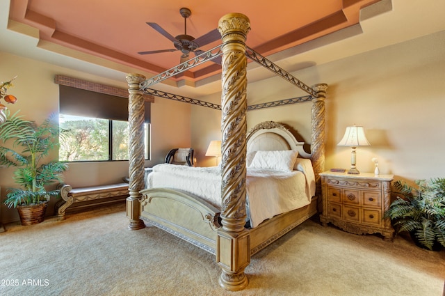 carpeted bedroom with ceiling fan and a tray ceiling