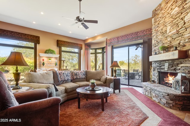 living room with ceiling fan, plenty of natural light, and a fireplace