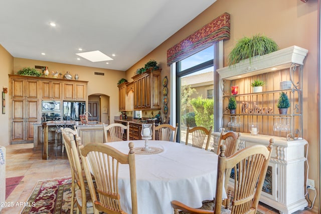 dining room featuring a skylight, light tile patterned flooring, and sink