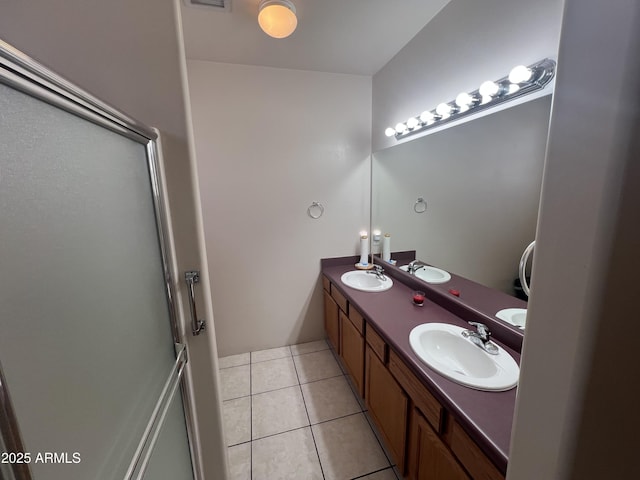full bath featuring a shower with shower door, tile patterned floors, and a sink