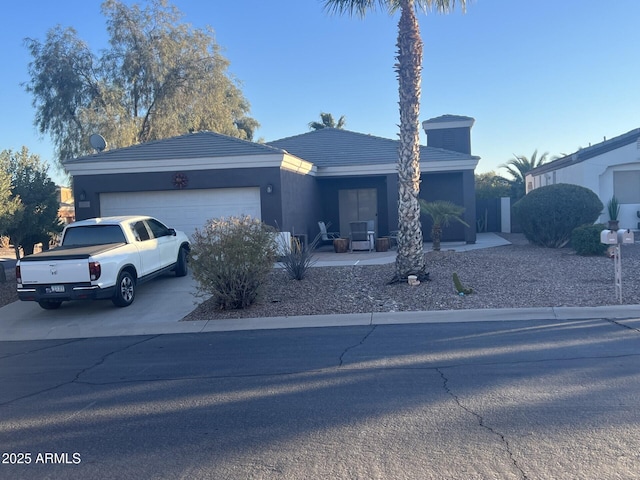 view of front facade with stucco siding, concrete driveway, a tiled roof, and a garage