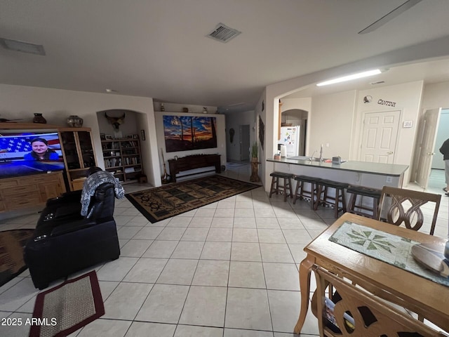 living area featuring arched walkways, visible vents, and light tile patterned floors