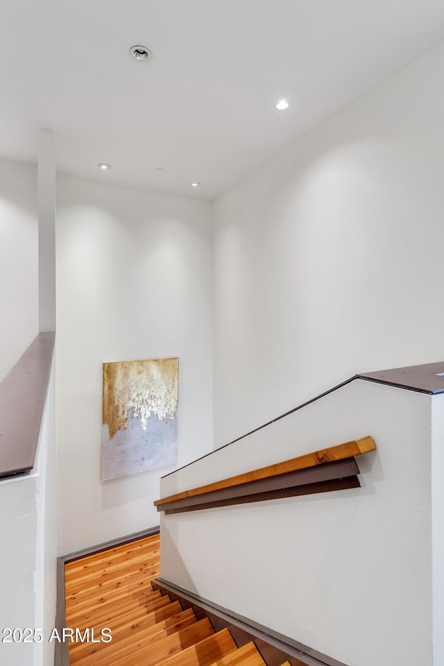 staircase featuring wood finished floors and recessed lighting
