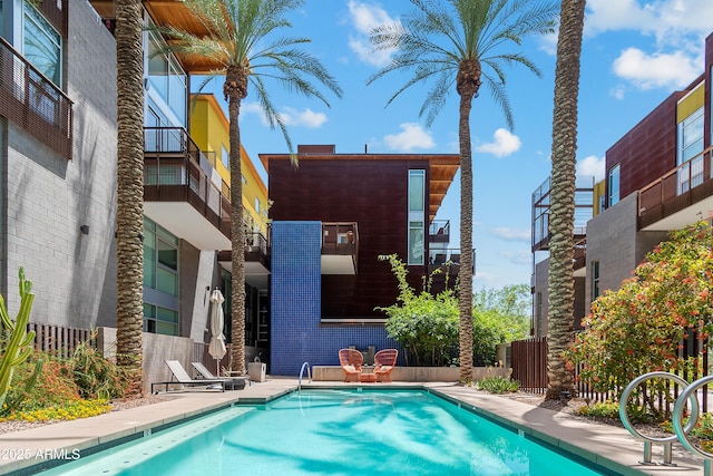 back of house featuring a community pool and fence