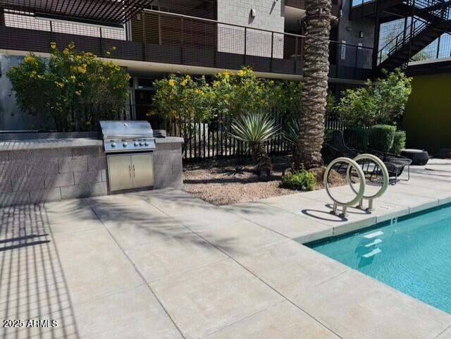 view of swimming pool featuring grilling area, an outdoor kitchen, a patio, and fence