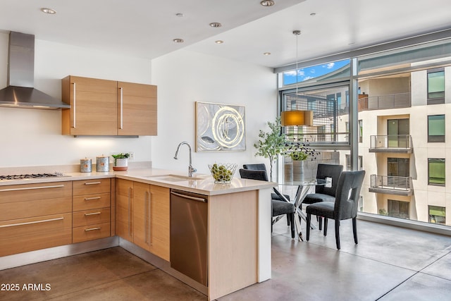 kitchen featuring wall chimney exhaust hood, a sink, dishwasher, concrete flooring, and gas stovetop