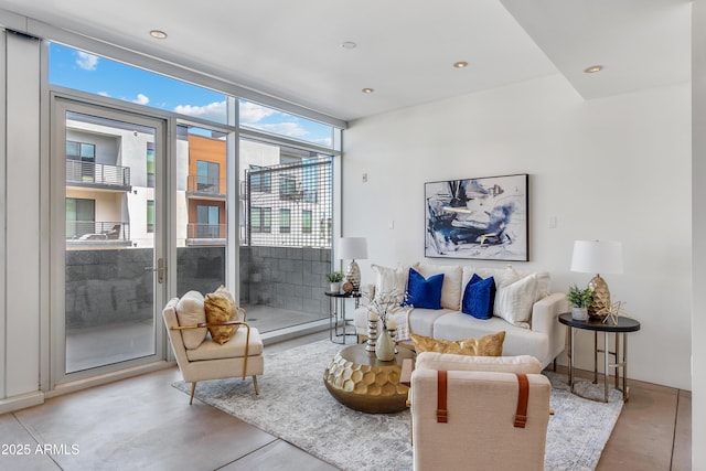 living area with finished concrete flooring, recessed lighting, and a wall of windows