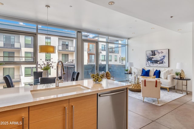 kitchen with a sink, dishwasher, open floor plan, a wall of windows, and light stone counters
