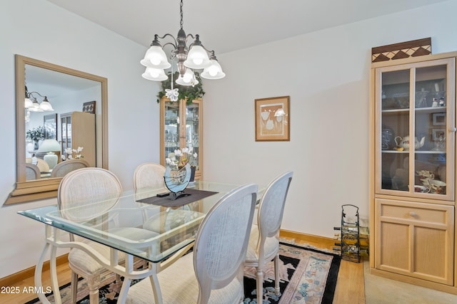 dining room with light hardwood / wood-style floors and a notable chandelier