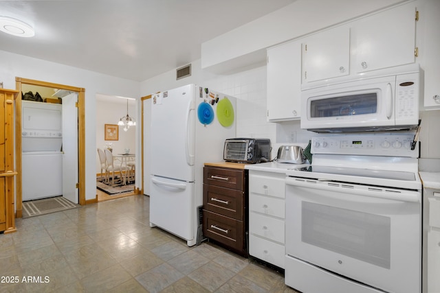 kitchen with white appliances, pendant lighting, stacked washer / drying machine, an inviting chandelier, and white cabinets