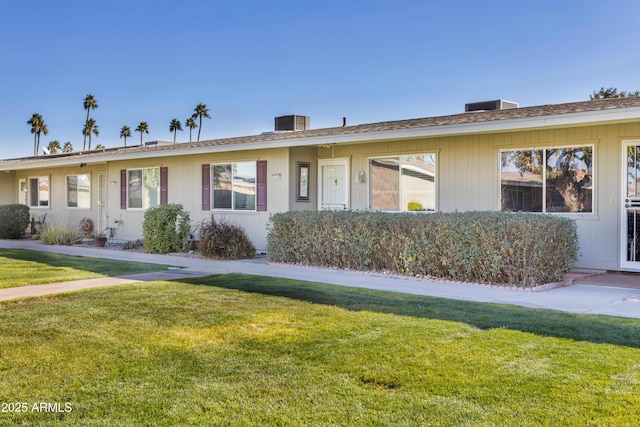 ranch-style house with a front yard and central AC unit