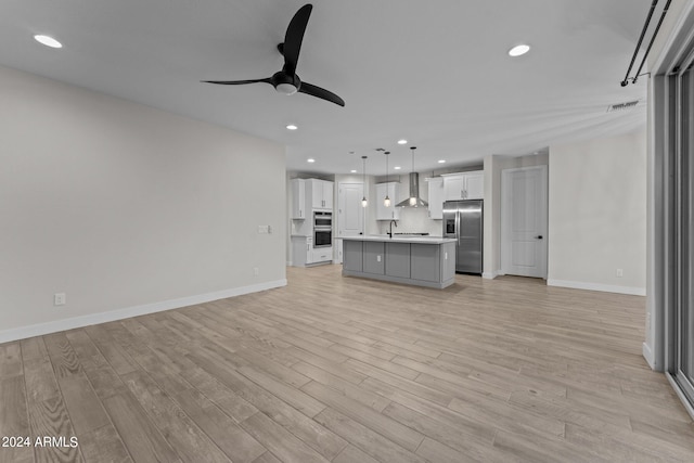 unfurnished living room with ceiling fan, sink, and light hardwood / wood-style floors