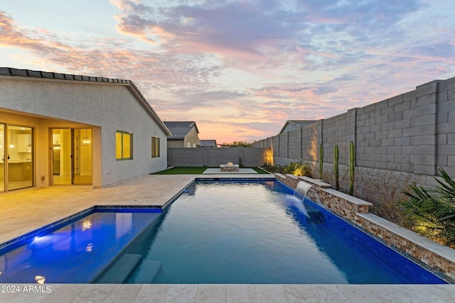 pool at dusk featuring a patio area and pool water feature