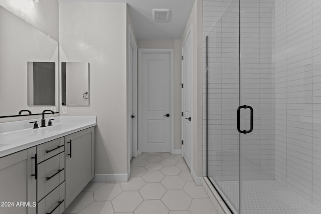 bathroom featuring vanity, a shower with shower door, and tile patterned flooring