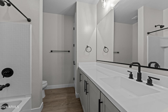 full bathroom featuring wood-type flooring, vanity, tiled shower / bath combo, and toilet