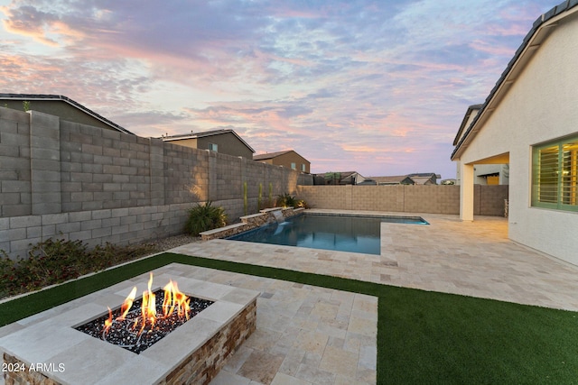 pool at dusk featuring a fire pit and a patio area