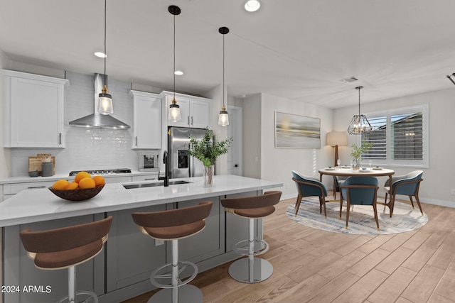 kitchen featuring appliances with stainless steel finishes, wall chimney exhaust hood, white cabinetry, and sink