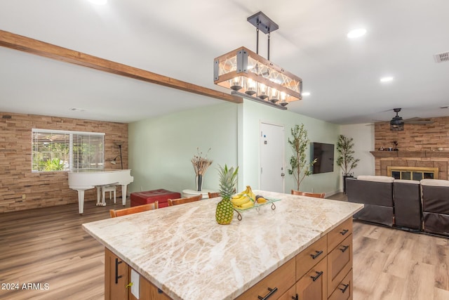 3136 W Sunnyside Ave, Phoenix, AZ 85029 - kitchen with hanging light fixtures, light stone countertops, a center island, and light hardwood / wood-style floors