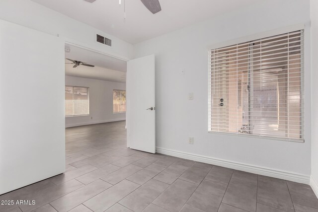 empty room with a ceiling fan, visible vents, and baseboards