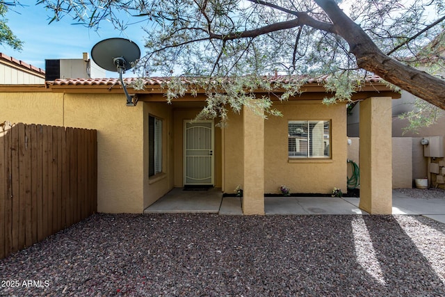 back of house featuring a patio area, fence, a tiled roof, and stucco siding