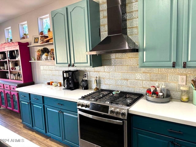 kitchen featuring light wood-type flooring, high end stove, wall chimney exhaust hood, and tasteful backsplash