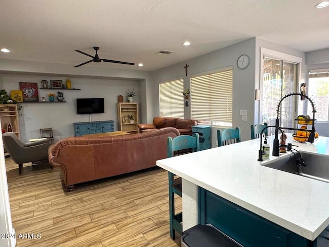 living room with light wood-type flooring, sink, and ceiling fan