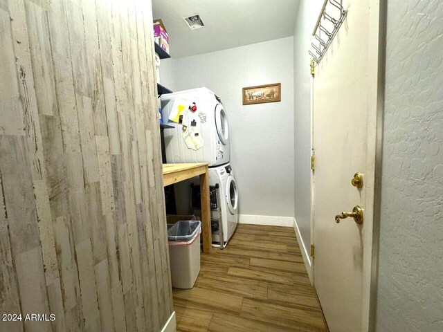 clothes washing area featuring stacked washer / dryer and light hardwood / wood-style flooring