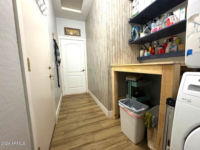 washroom with light hardwood / wood-style floors, wood walls, and washer / dryer