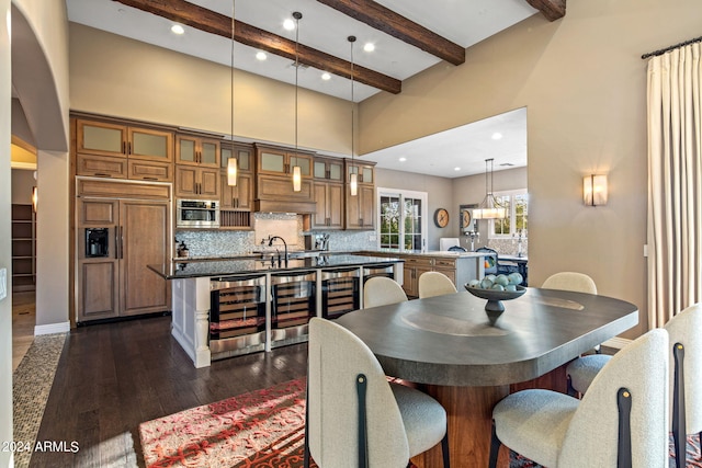 dining area with a towering ceiling, beamed ceiling, beverage cooler, and dark hardwood / wood-style flooring