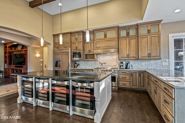 kitchen with high quality appliances, beverage cooler, dark stone countertops, dark hardwood / wood-style floors, and a kitchen island with sink