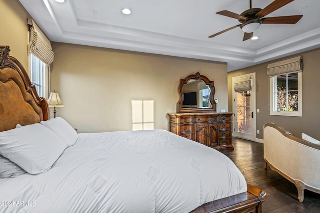 bedroom with dark hardwood / wood-style floors, a tray ceiling, and ceiling fan