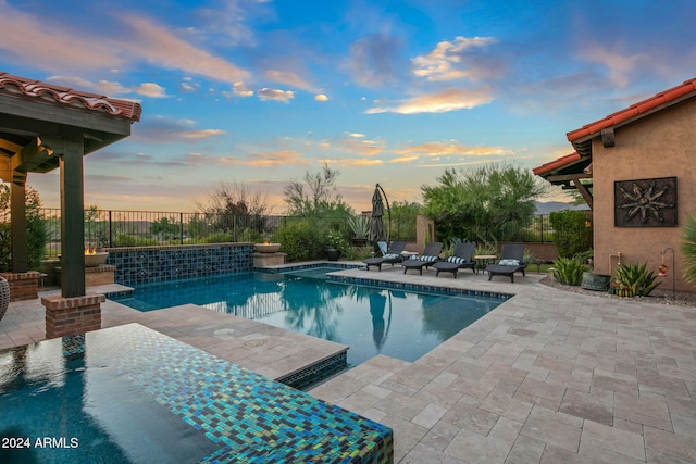 pool at dusk featuring a patio area