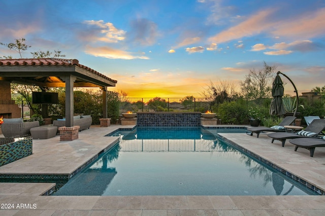 pool at dusk featuring a gazebo and a patio