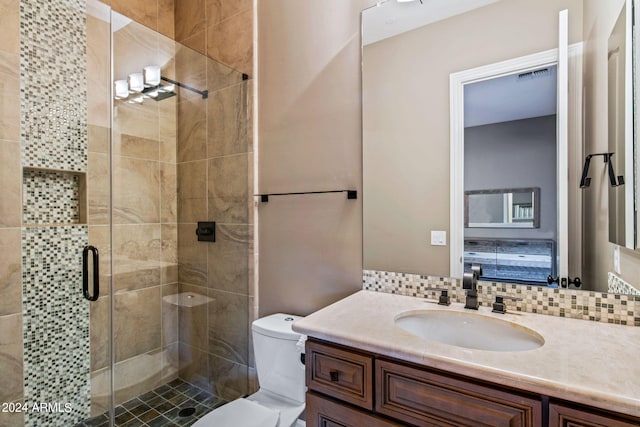 bathroom featuring vanity, decorative backsplash, a shower with shower door, and toilet