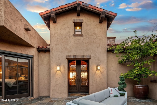 exterior entry at dusk with outdoor lounge area and a patio