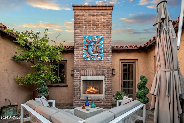 patio terrace at dusk featuring an outdoor living space with a fireplace