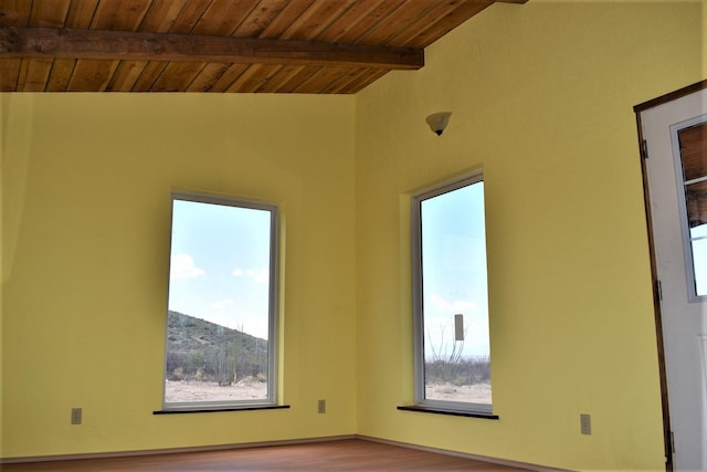 spare room with vaulted ceiling with beams, plenty of natural light, light wood-type flooring, and wood ceiling